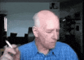 a bald man is smoking a cigarette in a blue shirt