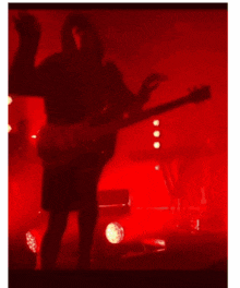 a person playing a guitar in a dark room with red lights