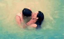 a man and woman are kissing in the water