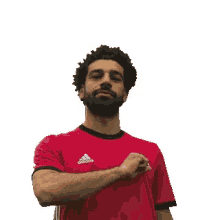 a man with a beard is wearing a red adidas shirt and giving a peace sign .