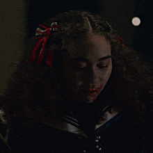 a girl with a red bow in her hair is smiling with blood on her face