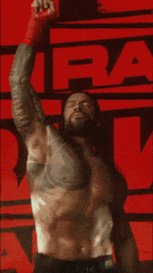 a shirtless wrestler is standing in front of a wwe logo