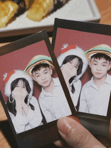 a person is holding a picture of a boy and a girl wearing santa hats