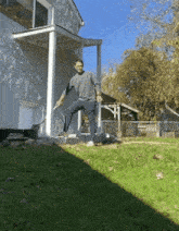 a man is standing in front of a white house holding a sword