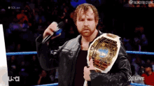 a man in a leather jacket is holding a world heavyweight wrestling championship belt