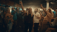 a group of people are holding up glasses of beer in a bar