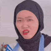 a woman wearing a hijab and an apron making a funny face .