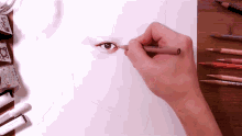 a person is drawing a woman 's eye with a pencil and erasers