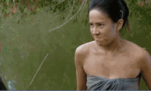 a woman without a shirt is talking to another woman near a body of water