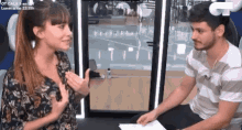 a man and a woman are sitting in front of a glass door talking to each other