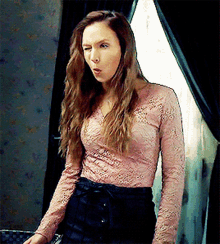 a woman wearing a pink lace top and black skirt