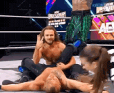 two men are wrestling in a wrestling ring and one of them is laying on the ground .