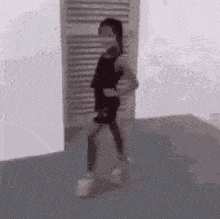 a woman is dancing in a room with a door in the background .