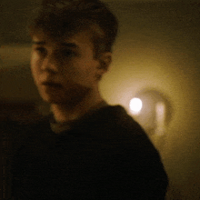 a blurry photo of a young man in a dark room with a light behind him