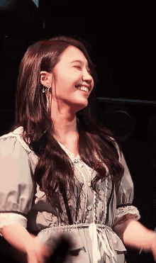 a woman in a grey dress is smiling and dancing