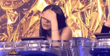 a woman is sitting in front of a drum set with her hand on her face .