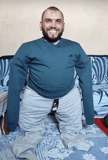 a man wearing a blue nike sweatshirt sits on a couch