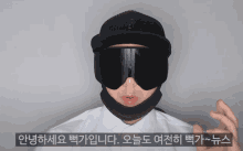 a man wearing a black hat and goggles with korean writing on the bottom right