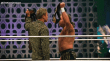 two wrestlers are standing in a ring with their championship belts .