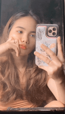 a woman taking a picture of herself in a mirror with a case that has leaves on it