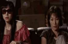 a woman wearing sunglasses is sitting next to another woman