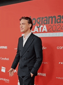 a man stands on a red carpet in front of a sign that says ' programas ata2024 '
