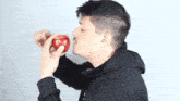 a man in a black hoodie is biting an apple