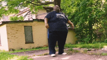 a man wearing a blue shirt with a picture of a bird on it stands in front of a building
