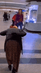 a woman in a sequined skirt is walking down a hallway at an airport .
