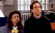 a man and a woman are sitting next to each other on a couch and looking at something .