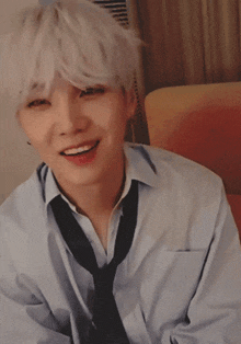 a young man with white hair and a tie smiles for the camera