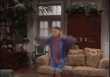 a man dancing in a living room with a couch