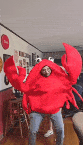 a man is standing in a living room wearing a red crab costume .