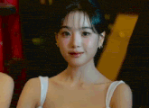 a close up of a woman 's face wearing a white tank top