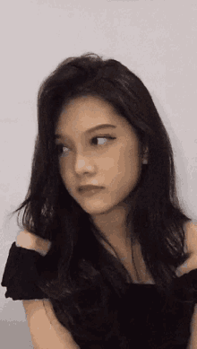 a woman with long dark hair is wearing a black off the shoulder top