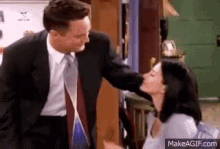 a man in a suit and tie kisses a woman on the cheek .