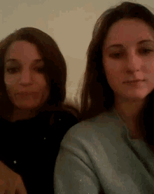 two women are sitting next to each other and one is wearing a sweater