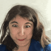 a woman wearing a blue shirt makes a funny face