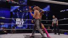 two men are wrestling in a wrestling ring while a referee looks on .
