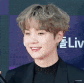 a close up of a person 's face with a smile on their face on a red carpet .