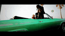 a woman is standing in the back of a green car