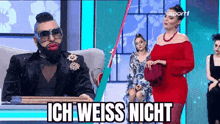 a man with a beard is sitting in front of a woman in a red dress on a television show .