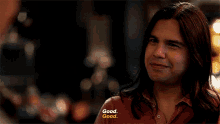 a man with long hair says good good in a dark room