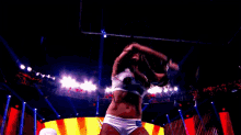 a female wrestler is holding a trophy in the air while standing on a stage .