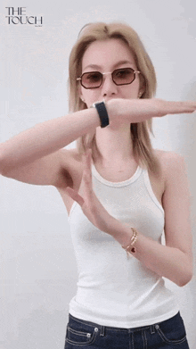 a woman wearing glasses and a white tank top is laughing