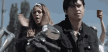 a man and a woman are standing next to each other on a motorcycle . the man is holding a red cup .