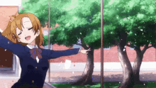 a girl in a school uniform is standing in front of a window with her arms outstretched and confetti flying around her .