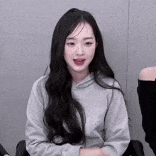 a girl with long black hair is wearing a grey hoodie with the letter k on it