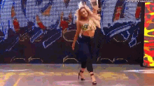 a woman is dancing on a stage in front of a large screen while wearing high heels .