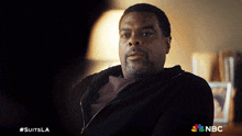 a man sitting in a dark room with a nbc logo on the bottom right